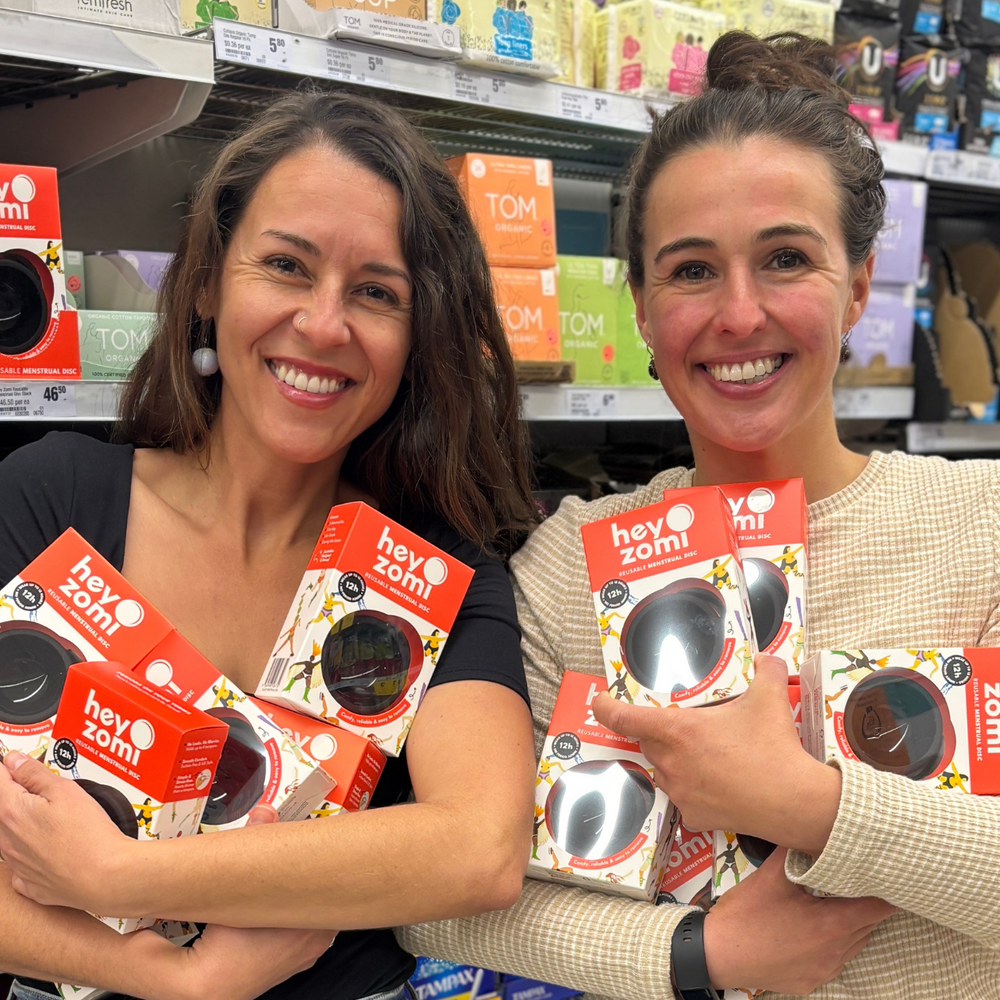 Hey Zomi is now in Woolworths - Mika and Zoe co-founders of Hey zomi in woolies with black menstrual discs on the shelf